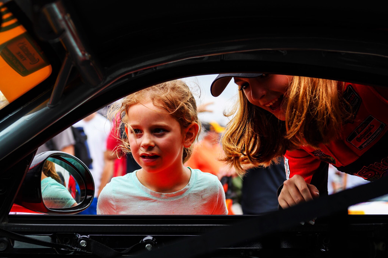Straus showing a young girl her race car. Photo credit: Wes Duenkel, used with permission